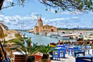 un port de plaisance avec des tables et des chaises et un moulin à vent dans l'établissement DX Appartamento Fiori d arancio, à Tonnara di Bonagia