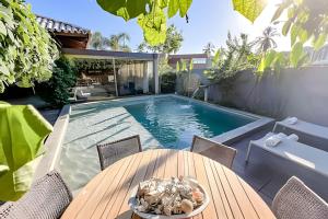 a patio with a table and a swimming pool at Casa com piscina aquecida, cozinheira, 30m do mar in Barra do Camaragibe