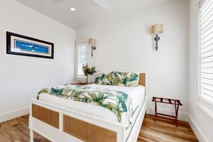 ein Schlafzimmer mit weißen Wänden und einem Bett mit tropischen Kissen in der Unterkunft Palmilla Opulence at Palmilla Beach in Port Aransas + 24 Fotos