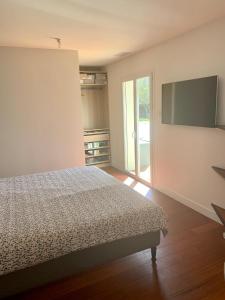 una camera da letto con un letto e una TV a schermo piatto di Villa au calme en lisière de forêt a Lacanau
