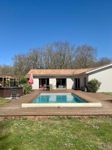 una piscina con terrazza e una casa di Villa au calme en lisière de forêt a Lacanau