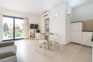 a white kitchen and living room with a table and chairs at Holiday Camelia in Pirri