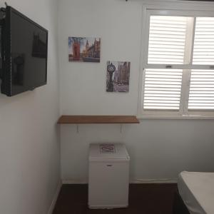 a white room with a tv and a window at Pousada Marduk excelente localização fotos atualizadas suites simples com banheiro privativo preço bom dispensamos hóspedes exigentes in Teresópolis