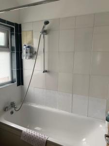a white bath tub with a shower in a bathroom at Large double room OVO Wembley stadium in London +13 photos