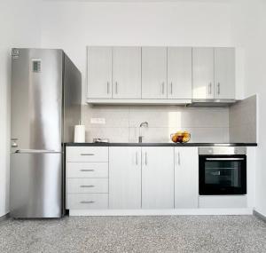 a kitchen with white cabinets and a stainless steel refrigerator at Linardo's Cycladic House in Naousa