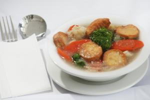 a bowl of food on a plate next to a fork at Genio Hotel Manado in Manado