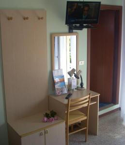 Cette chambre comprend un bureau avec un miroir et une télévision. dans l'établissement Hotel Fornaro, à Caorle