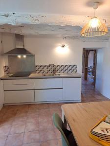 a kitchen with white cabinets and a table and a ceiling at Gîte Chaumière de Floranges 6 personnes Morbihan in La Chapelle-Neuve +17 photos