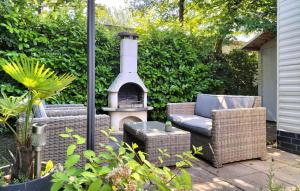 a patio with a fireplace and wicker chairs and a stove at 2 Bedroom Lovely Home In Heinkenszand in Heinkensand +22 photos