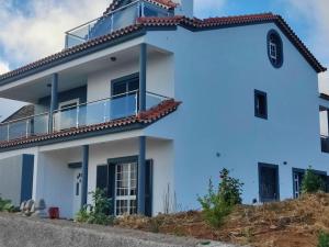 een wit huis met een balkon erbovenop bij Casa Neto Jardim in Calheta