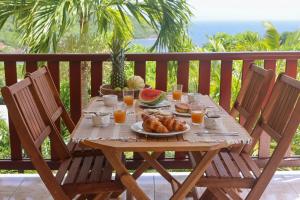 ein Holztisch mit einem Frühstück aus Obst und Saft in der Unterkunft Cottages Les 3 Rochers - Vue sur mer in Terre-de-Bas
