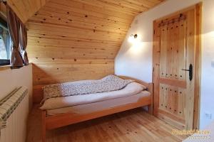 Habitación pequeña con cama y pared de madera. en PLANINSKI KUTAK Tara - Apartman 2, en Bajina Bašta