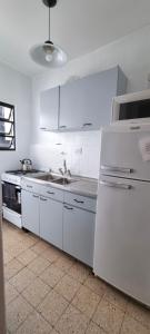a white kitchen with a sink and a refrigerator at Excelente ubicación en el Bv. más lindo de Rosario in Rosario