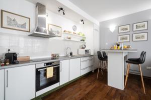 a kitchen with white cabinets and a counter with stools at City Center Wellness Suites - POOL-GYM-PARKING in Budapest