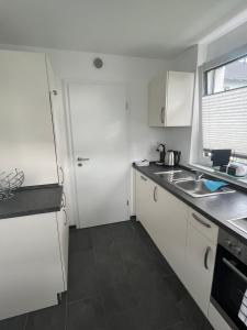 a white kitchen with a sink and a refrigerator at Ferienwohnung Klettgau-Erzingen in Klettgau