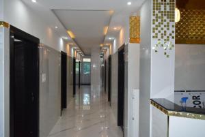 a hallway of a building with white floors and black doors at M Grand Stay in Coimbatore