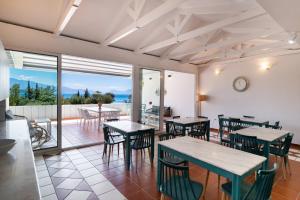 a restaurant with tables and chairs and a view of the ocean at Ionio Hotel in Nikiana