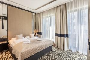 a hotel room with a bed and a large window at Ambria Apartments Promenada in Świnoujście