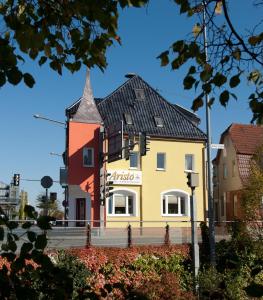 um edifício amarelo com um telhado preto em Aristo Hotel em Filderstadt