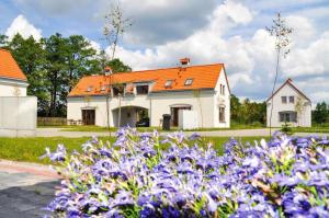 a white house with an orange roof and purple flowers at Dom Wrota Mazur in Pisz