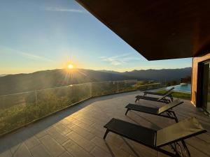 a balcony with benches and the sun setting on the mountains at Encosta do Gerês Village in Ventosa