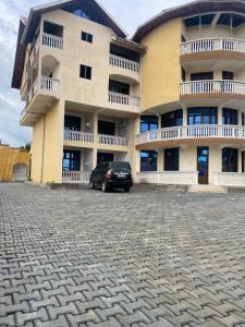 a large building with a car parked in front of it at Hotel new plazza in Kisangani