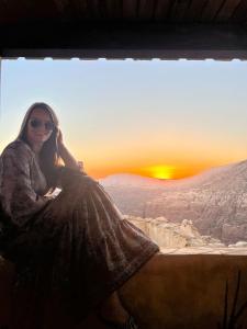 a woman sitting on a ledge watching the sunset at Dana Tower Hotel in Dana