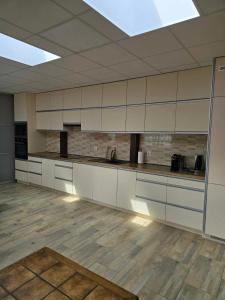a large kitchen with white cabinets and wooden floors at Apartamenty na 12 in Konstantynów Łódzki
