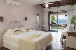 a bedroom with a white bed with a view of the ocean at Pousada Villa Agrifoglio in Praia do Rosa +82 photos