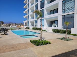 a swimming pool in front of a building at Lovely Condo Stunning Ocean View in Rosarito