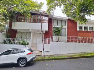 a white car parked in front of a red house at Carolina Hostel in San José