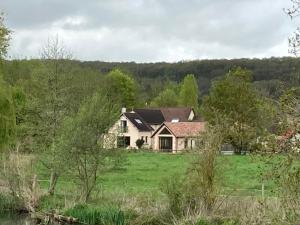 a house in the middle of a field with trees at Côté Rivière in Ézy-sur-Eure