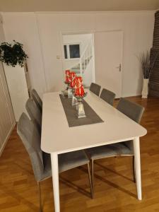 un tavolo da pranzo bianco con sedie e fiori rossi di Aadarsh Villa rom3, 10 min fra Oslo airport a Gjerdrum