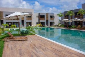 einem Pool mit Stühlen und einem Sonnenschirm neben einem Gebäude in der Unterkunft Villa Manatee Rota dos Milagres in Tatuamunha