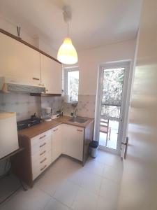a kitchen with white cabinets and a sink and a window at Chic & Calm apartment 3 minutes walk to Rafina Beach in Rafina