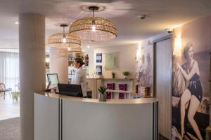 a woman standing at a counter in a salon at Best Western Les Bains Hotel et SPA in Perros-Guirec