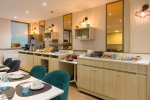 a restaurant with tables and chairs and a kitchen at Best Western Les Bains Hotel et SPA in Perros-Guirec