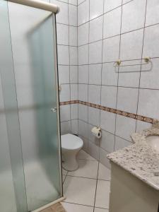 a bathroom with a toilet and a glass shower door at Linda Casa na Praia de Bombas in Bombinhas +12 photos