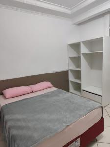 a bedroom with a bed with a pink pillow at Linda Casa na Praia de Bombas in Bombinhas