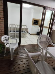 a deck with white chairs and a table and chairs at Linda Casa na Praia de Bombas in Bombinhas
