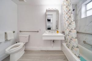 a white bathroom with a toilet and a sink at Deco Beachside Apt, w/2 Queen Beds, Washer/Dryer in Miami Beach +34 photos