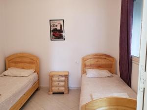 a bedroom with two beds and a night stand at Résidence Maya in El Haouaria