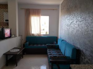 a living room with a blue couch and a window at Résidence Maya in El Haouaria
