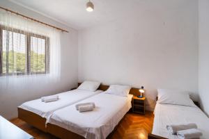 two beds in a room with two windows at Apartments with parking space Splitska, Brac - 2867 in Splitska