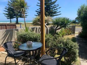 a table with two chairs and a table with a view of the beach at Beach Front Apartment in Ohope Beach