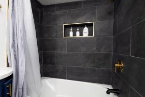 Un baño con bañera blanca y pared de azulejos negros. en 2 Bedroom Ft Moore Retreat, en Columbus 13 fotos más