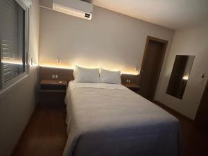 a small room with a bed with white sheets and a window at Casa Emma Gramado 3 in Gramado