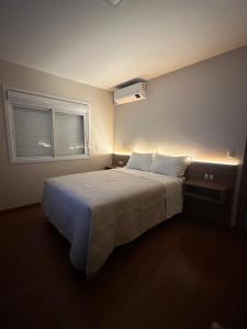 a bedroom with a large white bed with a window at Casa Emma Gramado 3 in Gramado