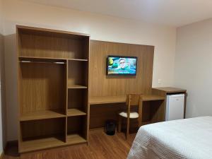 a bedroom with a bed and a desk and a tv at Casa Emma Gramado 3 in Gramado