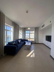 ein Wohnzimmer mit einem blauen Sofa und einem Fernseher in der Unterkunft هبة مارينا مدينة الملك عبدالله الاقتصادية in King Abdullah Economic City + 4 Fotos